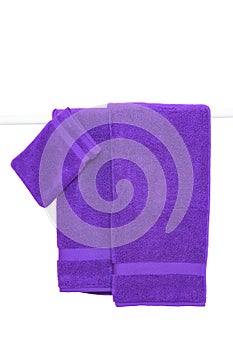 Hanging towels isolated. Closeup of purple soft terry bath towels hang on a clothes rail isolated on a white backgroun