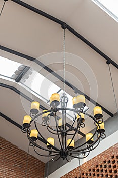 Hanging vintage black Chandelier ceiling with yellow lamp and brick wall interior