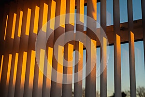 Hanging white textured vertical window slats reflecting the gold of a sunset