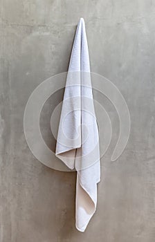 Hanging white towel draped on exposed concrete wall in the bathroom