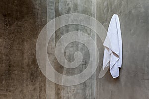 Hanging white towel draped on exposed concrete wall in the bathroom.
