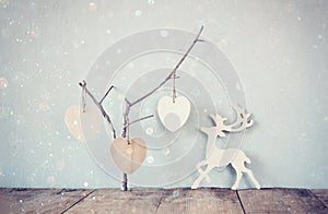 Hanging wooden hearts over and wooden rain deer decoration over wooden background. retro filtered image