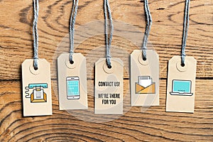 Hangtags on wooden background with message CONTACT US! WE ARE THERE FOR YOU photo