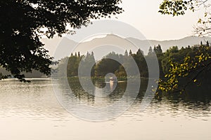 Hangzhou, China - November 9 2019: Beautiful scenic view by the West Lake at sunset, touristic boats sailing on the lake