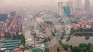 HANOI, VIETNAM - APRIL, 2020: Aerial drone view of the railroad overpass with station and cityscape of Hanoi near lake.