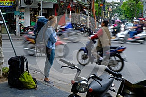 Hanoi / Vietnam, 05/11/2017: Backpacker watching busy hectic traffic with passing cars and motorbikes on a Hanoi street