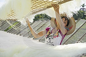 Hanoi, Vietnam - July 13, 2014: Unidentified woman dries vermicelli made from rice flour. Vermicelli is an ingredient of Vietnames