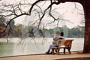 Hanoi, Vietnam - 10 March, 2012: The couple sit on the bench at Hoan Kiem lake