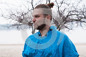 Hansome bearded man with hair bun and make up looking away and speaking