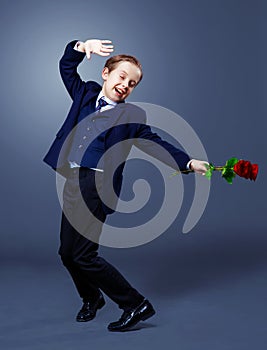 Hansome boy wearing a black suit with roses in his hands