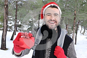 Hansome man holding Christmas present in the snow
