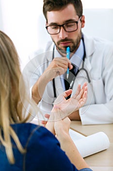 Hansome young male doctor checking hand pain for patient in the medical office.