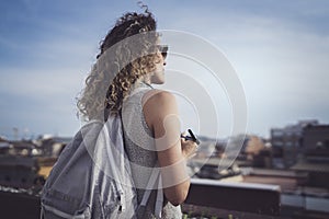 Hansome young woman curly hair and casual wear enjoing beautiful view of the city on sunset.