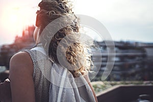 Hansome young woman curly hair and casual wear enjoing beautiful view of the city on sunset.