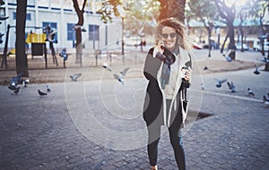 Hansome young woman hipster using smart phone, during walking in european city. Bokeh and flares effects on blurred