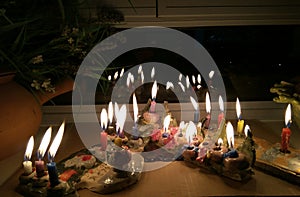 Hanukka candeles lit on a window shelf photo