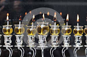 Hanukkah candles are lit in a silver menorah against the backdrop of the darkness