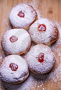 Hanukkah food doughnuts with jelly and sugar powder on wooden background. Jewish holiday Hanukkah concept and background.