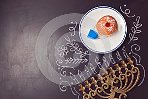 Hanukkah holiday background with menorah and sufganiyot over chalkboard. View from above