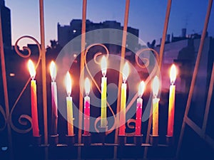 Hanukkah menorah with burning candles outside open window with metal latticework. photo