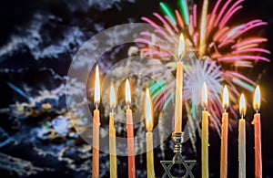 Hanukkah menorah with candles, colorful firework sky background photo