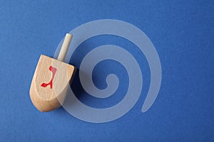 Hanukkah traditional dreidel on blue background, top view. Space for text