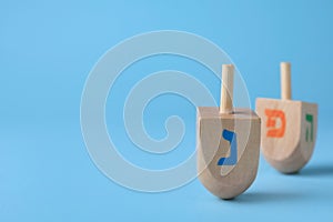 Hanukkah traditional dreidel with letter Nun on light blue background, space for text