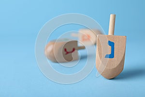 Hanukkah traditional dreidel with letter Nun on light blue background, space for text