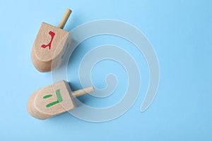 Hanukkah traditional dreidels on light blue background, flat lay. Space for text