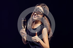 Happe woman in mask holding glass with champagne