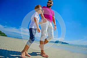 The happiest childhood: father and son walking along the tropical beach