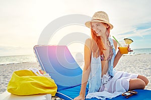 The happiest days are had at the beach. an attractive young woman lounging on the beach and enjoying a cocktail.