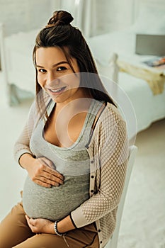 Happily looking woman touching her pregnant belly
