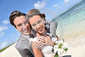 Happily married newly-weds on the beach smiling
