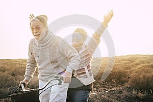 Happiness for active senior retired people lifestyle concept - joy old aged caucasian couple riding together a bika laughing and