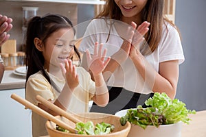 Happiness asian family with father, mother and daughter preparing cooking salad vegetable food together in kitchen.