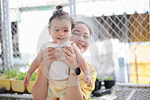 Happiness Asian mother holding a cute little baby girl on blurred background , baby smile and looking at camera
