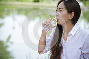 Happiness Beautiful asian chinese women holding mineral water bottle. Young Woman Drinking Water from bottle in green garden Park