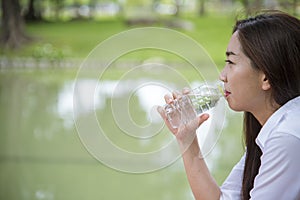 Happiness Beautiful asian chinese women holding mineral water bottle. Young Woman Drinking Water from bottle in green garden Park