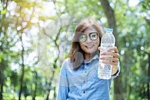 Happiness Beautiful asian chinese women holding mineral water bottle. Young Woman Drinking Water from bottle in green garden Park
