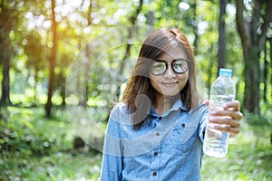 Happiness Beautiful asian chinese women holding mineral water bottle. Young Woman Drinking Water from bottle in green garden Park