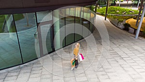 happiness, consumerism, sale and people concept - smiling young woman with shopping bags over mall background