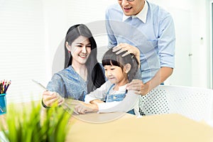 Happiness family leisure time in living room togetherness .Asian family having good time at home sitting on desk, playing ,drawing