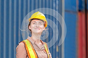 Happiness Female engineer in hardhat and safety vest smiling and looking at sky, Factory worker woman at container cargo