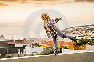 Happiness and freedom concept for independent young beautiful woman walking balanced on a wall with city and sea coast in
