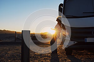 Happiness and freedom life with woman against camper van and golden sunset in background. People enjoying vanlife and summer