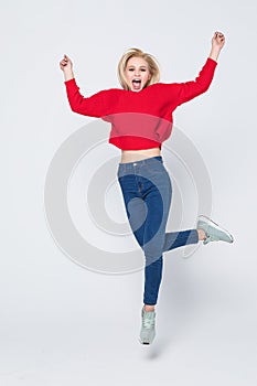 Happiness, freedom, power, motion and people concept. Smiling young woman jumping in air with raised fists over white background