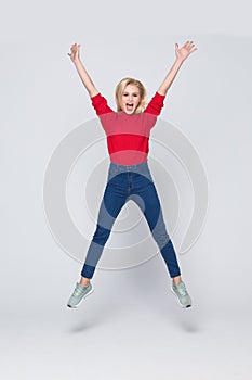 Happiness, freedom, power, motion and people concept. Smiling young woman jumping in air with raised fists over white background