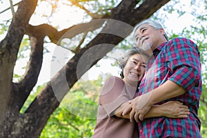 Happiness Grandparents asian couple. Grandfather and grandmother embracing each other with love and smiley faces under tree. Elder