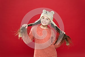 Happiness and joy. Winter outfit. Small child long hair wear hat red background. Cute model enjoy winter style. Adorable